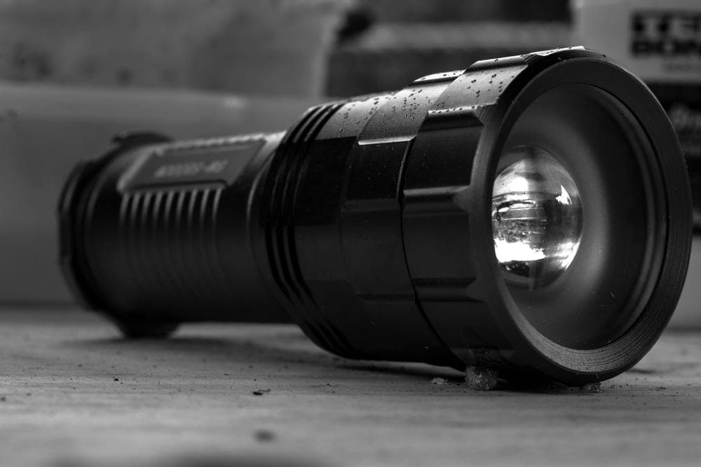 Black-and-white close-up of a flashlight on a textured surface